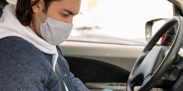 man with mask on in car